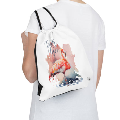 Unleash your wanderlust with our versatile drawstring backpack! Embrace travel with ease and style, flaunting a Beach Life Flamingo graphic with bright color backgrounds. This one is a white background. Designed for adventurers, it's the perfect blend of practicality and fashion. Get yours today for your next adventure! This is a front view of the backpack on the back of a model. 