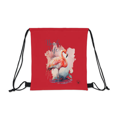 Unleash your wanderlust with our versatile drawstring backpack! Embrace travel with ease and style, flaunting a Beach Life Flamingo graphic with bright color backgrounds. This one is a red background. Designed for adventurers, it's the perfect blend of practicality and fashion. Get yours today for your next adventure! This is a front view of the backpack. 