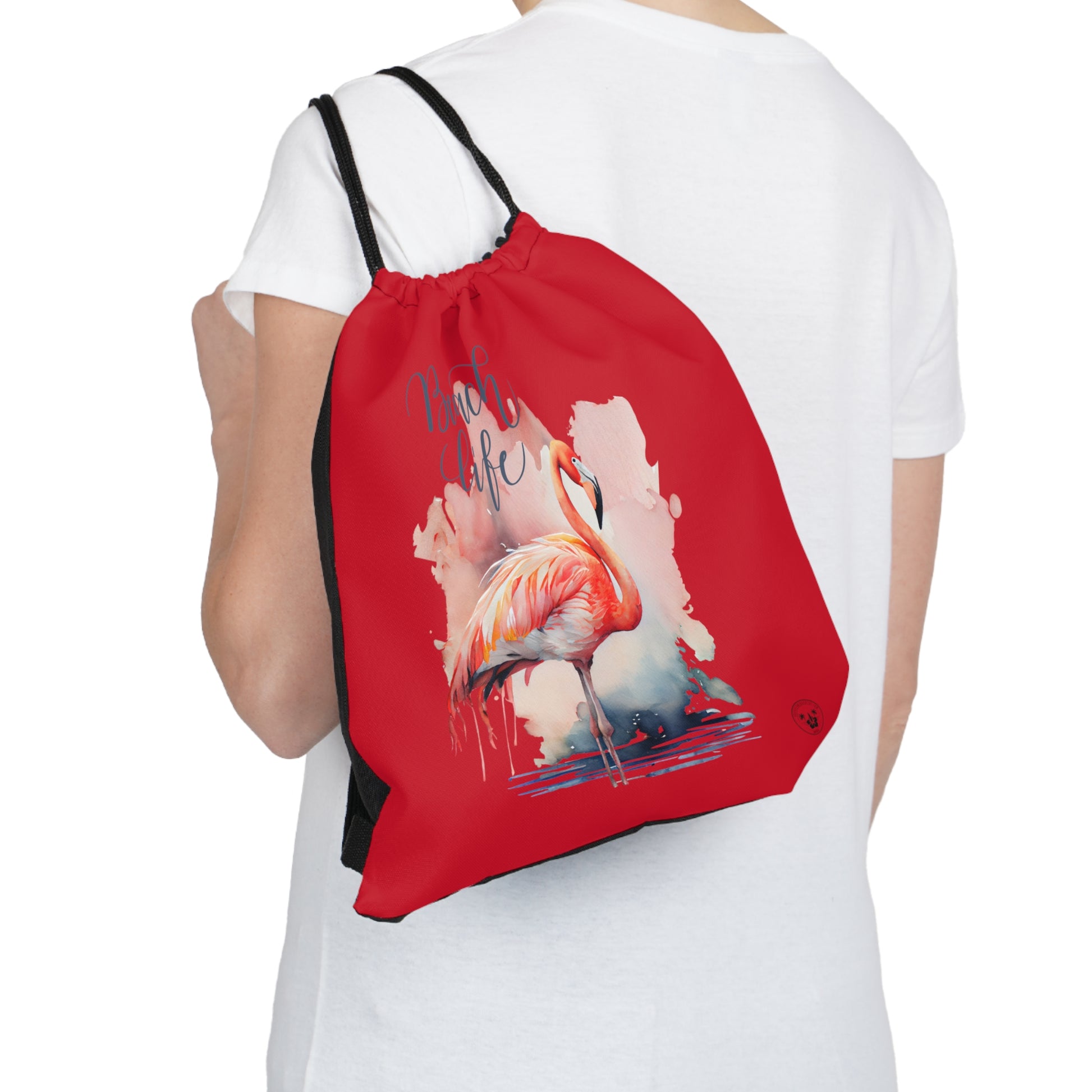 Unleash your wanderlust with our versatile drawstring backpack! Embrace travel with ease and style, flaunting a Beach Life Flamingo graphic with bright color backgrounds. This one is a red background. Designed for adventurers, it's the perfect blend of practicality and fashion. Get yours today for your next adventure! This is a front view of the backpack on the back of a model. 